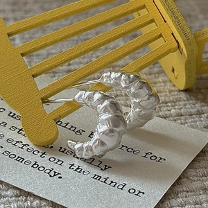 S925 sterling silver croissant hoop earrings with matte finish on a mini yellow chair