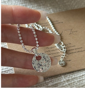 Macro shot of 925 sterling silver hammered ring pendant on a beaded necklace chain