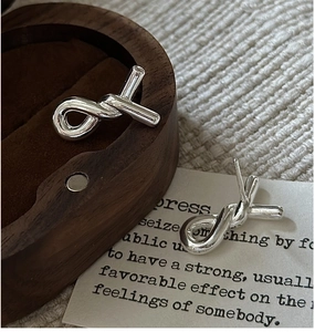 Macro detail of S925 sterling silver twisted knot earrings on a wooden jewelry box
