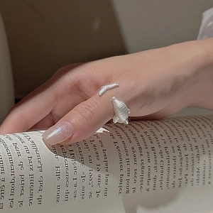 S925 sterling silver manatee wrap ring with matte finish on hand over an open book