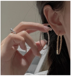 Détail des créoles à texture bambou or et argent et bague perlée sur un mannequin