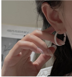 Close-up of minimalist white matte hoop earrings worn by a model for elegant style