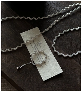 Detail shot of a S925 sterling silver wavy ring with fine chain and ball pendant