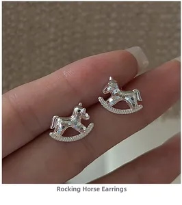 Detailed macro view of silver rocking horse earrings held by hand showing hammer texture