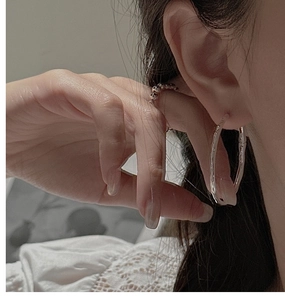 Gros plan de créoles en argent S925 avec une texture unique de style bambou épuré