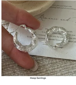 Detail of twisted S925 sterling silver hoop earrings with hollow woven texture