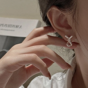 Minimalist S925 sterling silver knotted cross stud earrings worn by a female model