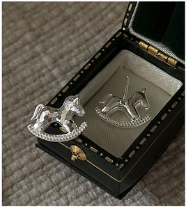 Macro shot of silver rocking horse earrings with sparkling glitter in a vintage box