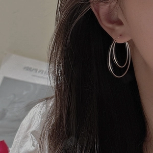 Minimalist S925 sterling silver double hoop earrings worn by a model in warm light