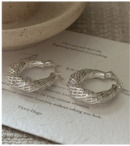 Macro shot of S925 sterling silver twisted hoop earrings with hallmark and metal texture