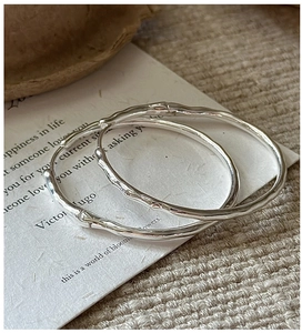 Détail macro de boucles d'oreilles créoles en argent S925 avec texture bambou vintage
