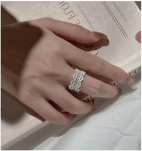 Detail of vintage lace hollow silver ring band worn on finger with elegant aesthetic