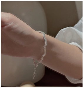 Macro detail of S925 sterling silver wavy braided bracelet with elegant metal texture