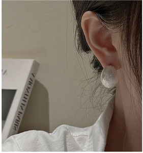 Close-up of textured S925 sterling silver ball stud earring on ear with minimalist finish
