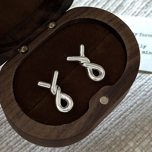 Minimalist S925 sterling silver twisted knot stud earrings on a velvet jewelry box display