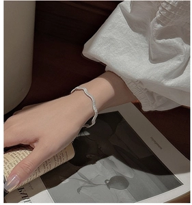 Close-up of a minimalist wavy S925 silver bracelet with irregular textured design on wrist