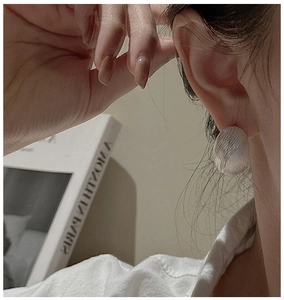 Detail of S925 sterling silver ball earring with textured finish on model