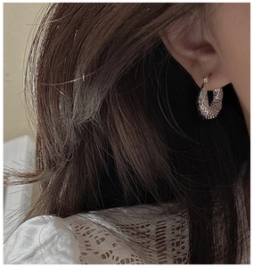 Detailed view of silver twisted hoop earrings with elegant woven texture on a model