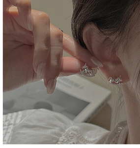 Macro shot of S925 sterling silver rocking horse stud earrings worn on a model