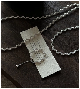 Detail of S925 sterling silver wavy chain and beaded ring on vintage wood surface