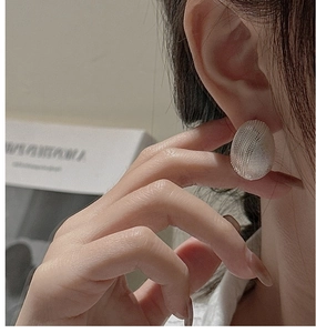 Macro detail of silver S925 oval earring with fine mesh texture shown on ear