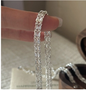 Macro shot of S999 silver shimmering woven chain bracelet with vintage glossy texture