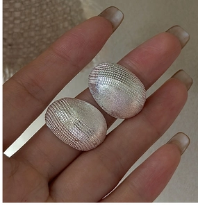 Detailed close-up of S925 silver oval earrings with unique grid and matte textures