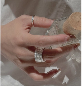 Détail d'une bague large texturée et anneau géométrique en argent S925 sur le doigt