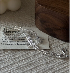Detailed view of S999 sterling silver braided chain with lobster clasp on a textured surface