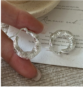 Detailed macro view of S925 sterling silver hoop earrings with hollow twisted mesh design