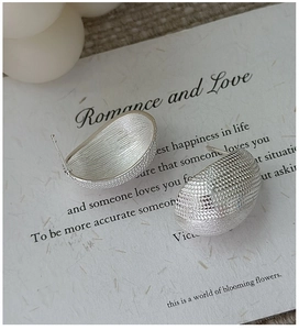 Detailed macro view of S925 sterling silver earrings with cross-textured matte finish
