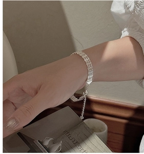 Détail du bracelet tressé multicouche en argent S999 avec breloque cœur au poignet