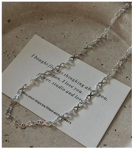 Detailed close-up of S925 silver necklace with minimalist infinity cross link design