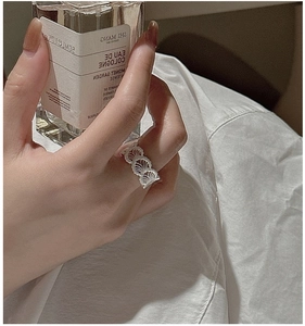 Detail of silver lace texture ring with shell patterns shown on a model hand