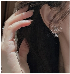 Macro side view of silver tassel earrings with fireworks design and delicate bead chains
