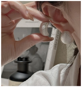 Close-up of S925 silver crescent earrings with textured mesh finish on a model