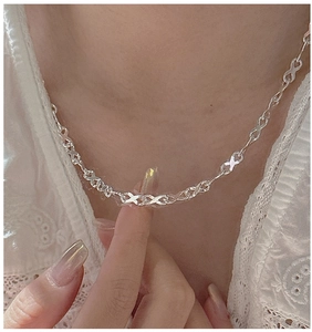 Detail of silver infinity link chain necklace worn with a white lace collar