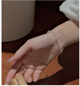 Detail of silver wavy twisted bracelet and matching ring on model with warm shadows