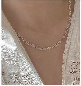 Detail of silver S925 interlocking X-link necklace on model wearing white lace