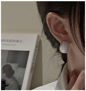 Detail of S925 sterling silver ball earrings with brushed texture on model's ear