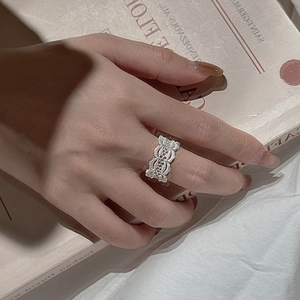 Elegant S925 sterling silver vintage lace hollow ring on a model's finger with retro books