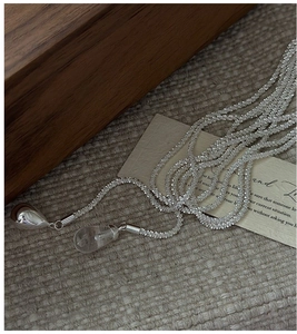Macro detail of S925 silver chain with crystal teardrop pendants on a rustic wood surface