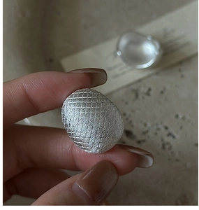 Macro shot of silver ring featuring irregular pebble shape and brushed grid texture