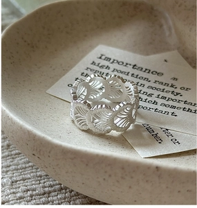 Macro view of S925 sterling silver ring with delicate lace texture on ceramic plate