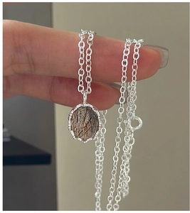 Macro view of S925 sterling silver necklace with a claw-set rutilated quartz pendant