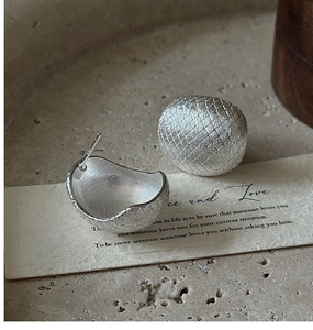Macro detail of S925 sterling silver earrings with brushed woven texture on stone