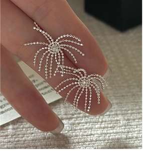 Macro shot of S925 silver fringe earrings with sparkling fireworks design in hand