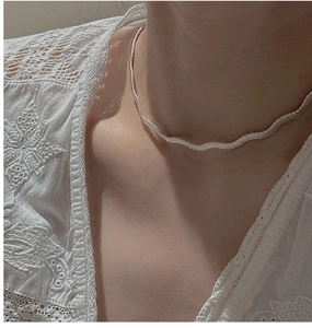 Détail du collier en argent sterling S925 à texture tissée porté sur un fond en dentelle