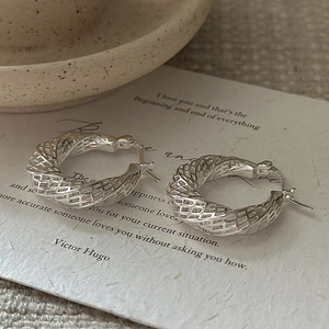 Elegant S925 sterling silver hollow twisted hoop earrings on vintage paper background