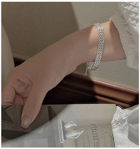 Detail of silver S999 multilayer mesh bracelet with heart pendant on a woman's wrist